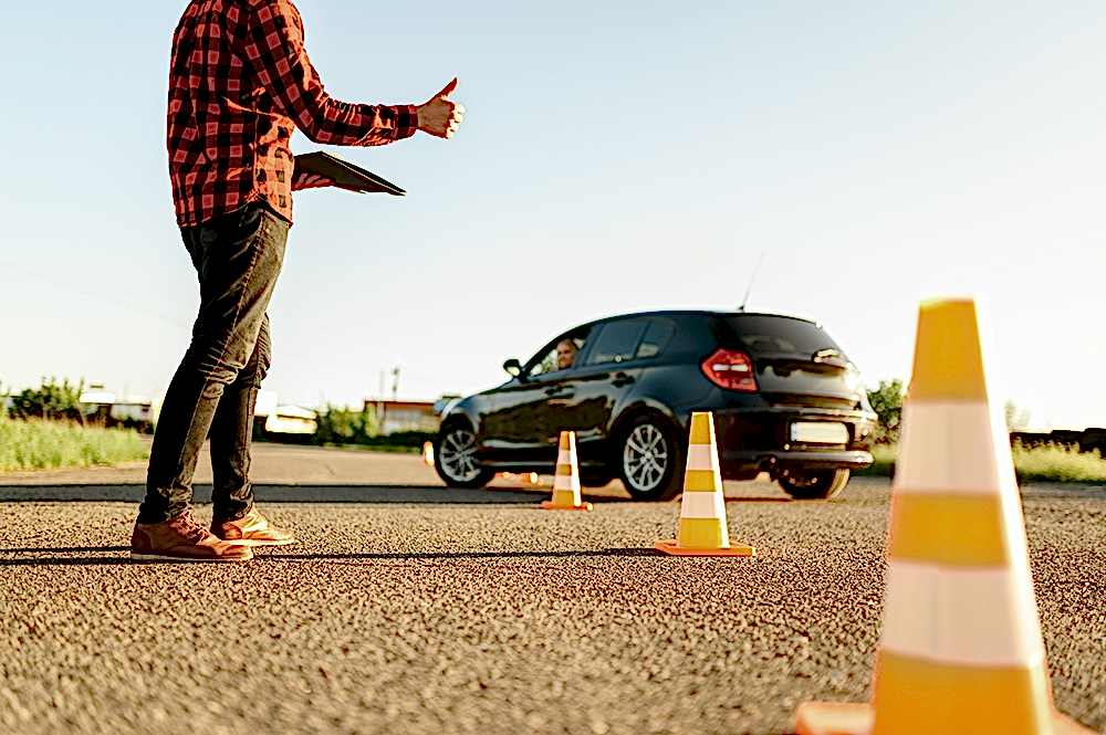 Instructor helps female student to drives between cones, lesson in driving school. Man teaching lady. Driver's license education